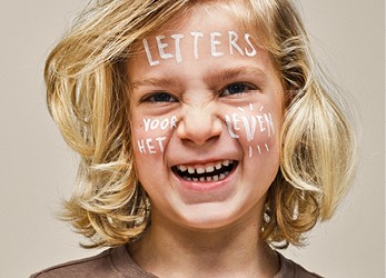 Een lachende jongen met 'letters voor het leven' op zijn gezicht geschreven